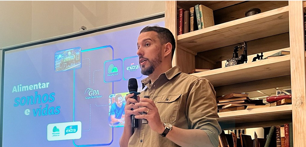 Beto apresentando com microfone diante de um telão com marcas do GPA